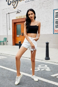 Detail of white high-waisted denim shorts with frayed edges and ripped texture for women