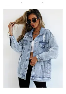 Close-up of distressed light blue denim jacket with vintage ripped holes and metal buttons