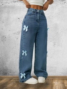 Dettaglio dei jeans dritti a vita alta con fiocchi in seta azzurra applicati lateralmente