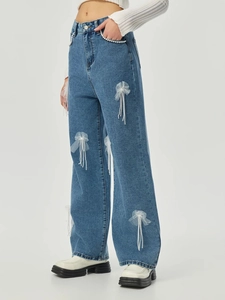 Detail von hellblauen Jeans mit Tüllschleifen und Perlenquasten für Damen