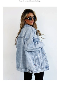Detail of distressed light blue oversized denim jacket with washed textures and ripped design
