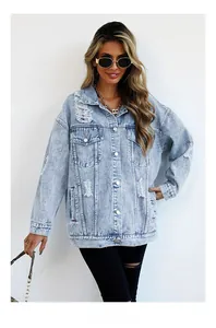Detail of light blue washed denim jacket with distressed ripped holes and metal buttons