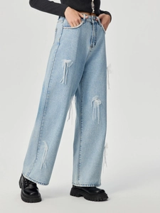 Detailansicht der hellblauen Jeans mit weißen Netzschleifen und Perlenquasten-Anhängern