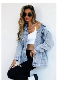 Detailed view of light blue distressed denim jacket featuring metal buttons and pockets