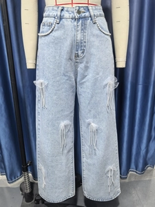 Detail von hellblauen Jeans mit Perlenfransen und weißen Netz-Schleifen aus Mesh-Gewebe