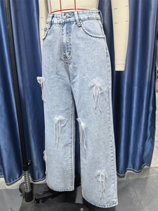 Detailansicht der hellblauen Jeans mit weißen Perlen und Schleifen aus weißem Netzstoff