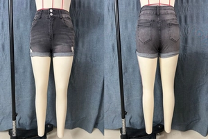 Detail of dark gray low-waisted denim shorts with cuffed hems and distressed ripped details