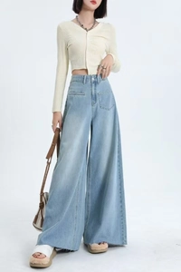 Detail of high waisted wide leg light blue jeans with a square front pocket and raw hem