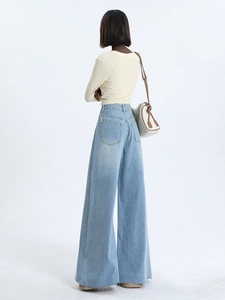 Close-up of light blue wide-leg jeans with vintage washed texture and frayed hem detail
