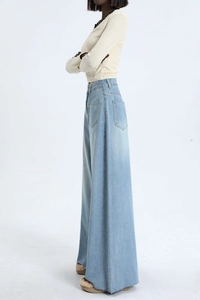 Detail of high-waisted wide-leg jeans with side pocket and raw hem edges in light blue