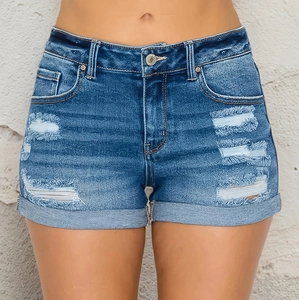 Macro detail of ripped blue denim shorts featuring frayed holes and folded hems