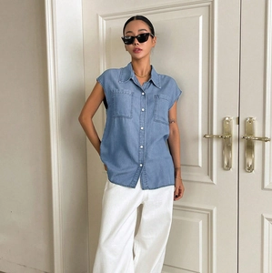 Detail of light blue sleeveless denim shirt with turn-down collar and two chest pockets