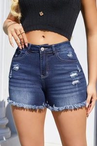 Dettaglio degli shorts in denim blu scuro con strappi usurati e bordi con frange