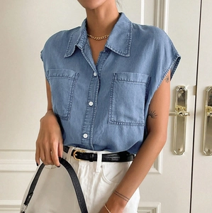 Close-up of washed blue denim shirt with white buttons and large chest pockets