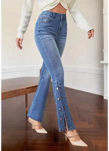 Close-up of retro flare jeans featuring side slits and silver metal buttons at the hem