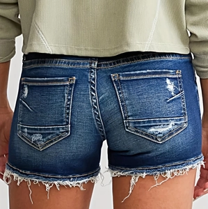 Détail des poches arrière usées et des ourlets effilochés sur ce short en jean bleu