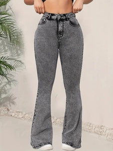 Gros plan sur le jean évasé gris délavé à taille haute avec bouton en métal et texture denim