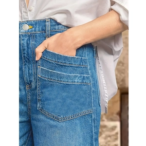 Detail of high waist denim jeans featuring large patch pockets and contrast stitching