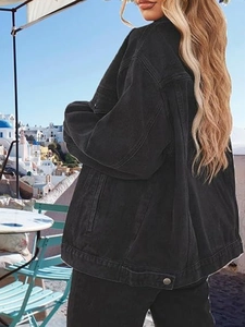 Outdoor street style shot of a woman in an oversized black denim jacket with side pockets