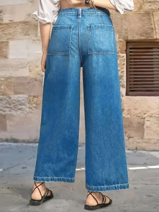 Rear view of high-waisted blue wide-leg jeans with back pockets on a brick background