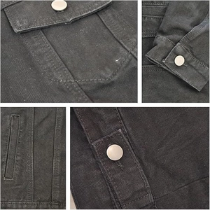 Detailed macro view of black denim jacket silver buttons and reinforced pocket stitching
