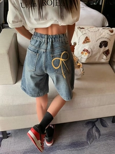 Détail du short en jean avec taille élastique et imprimé nœud jaune sur la poche arrière