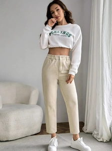Close-up of women's casual outfit with white slogan sweatshirt and beige elastic waist jeans
