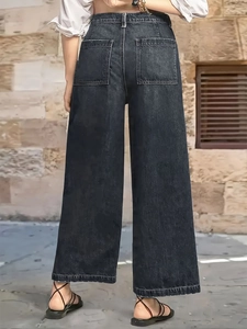Detail of high waisted wide leg jeans showing rear square pockets and washed denim texture