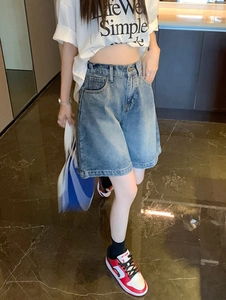 Détail d'un short en jean bleu taille haute avec délavage vintage et bouton en métal