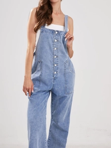 Detail of light blue denim overalls showing metal buttons and loose wide-leg cut