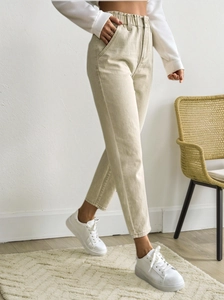 Detailed view of elastic high waistband and side pockets on beige slim fit casual trousers
