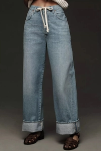 Detail of light blue wide-leg jeans featuring waist drawstring and large cuffed hems