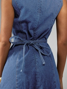 Detail eines blauen Jeanskleides mit Schnürung an der Taille und verstellbarer Schleife