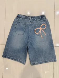 Détail du short en jean à taille haute avec imprimé nœud orange sur la poche arrière