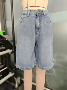 Détail de short en jean bleu clair délavé avec bouton métallique et passants de ceinture