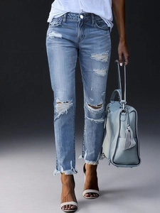 Detail der hellblauen Jeans mit zerstörtem Kniebereich und ausgefranstem Saumrand