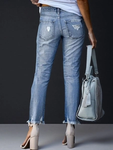 Detailansicht der hellblauen Jeans mit ausgefransten Säumen und Rissen an den Taschen