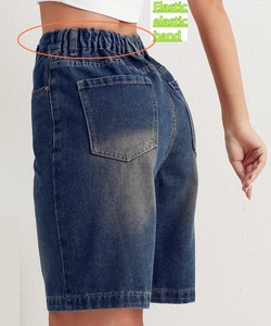 Detail of high-waist elastic band on dark blue washed denim shorts with stitching