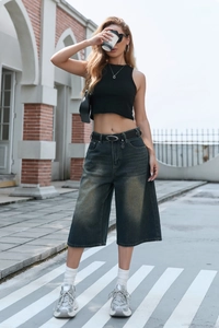 Detail of high-waist vintage washed wide-leg denim culottes with a black leather belt