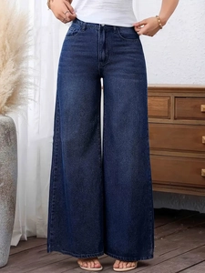 Detail of high-waist wide-leg jeans in dark blue wash with vintage fade and drape effect