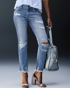 Detail der hellblauen Jeans mit Rissen und ausgefransten Säumen im Denim-Stil