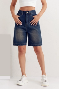 Detail of high-waisted dark blue denim shorts with natural washed texture for women