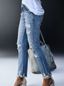 Detail einer hellblauen Skinny Jeans mit Rissen am Knie und offenen Saumkanten