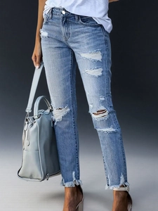 Detail der hellblauen Jeans mit Fransen am Saum und modischen Rissen im Denim-Stoff