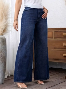 Detail of high-waisted dark blue wide-leg jeans with washed denim texture on a model