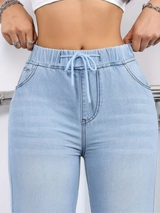 Detail of high waist light blue denim joggers with elastic drawstring waistband