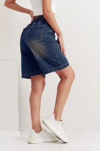 Detail of high waist elastic waistband and rear pockets on blue denim shorts