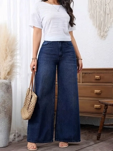Close-up of deep blue high-waist wide-leg jeans styled with a woven straw bag