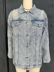 Detail view of light blue washed denim jacket with distressed ripped holes and metal buttons