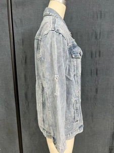 Detail of light blue distressed denim jacket with vintage wash and ripped textures